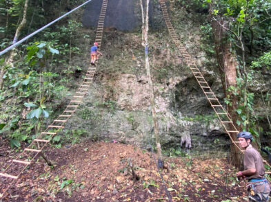 Man climbing on huge rope ladder going up a hill in nature